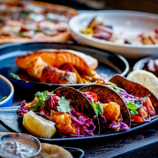 A close-up of Craft Kitchen + Bar's fish tacos with red cabbage, cilantro, and lime.