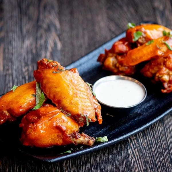 Craft Kitchen + Bar's buffalo wings, garnished with herbs, served with a side of ranch.