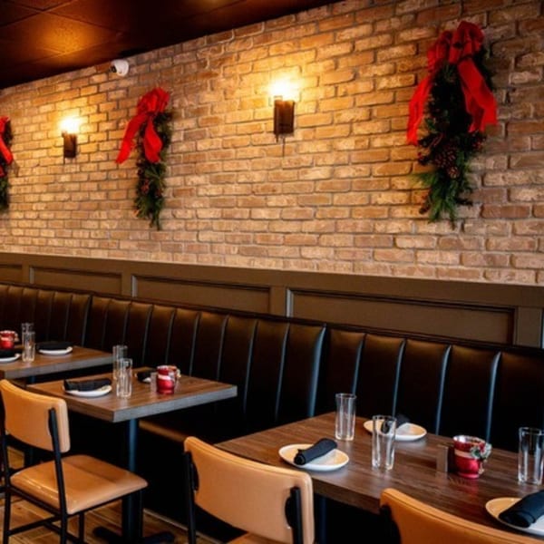 Cozy dining area at Craft Kitchen + Bar with brick walls, booth seating, and festive holiday decor.