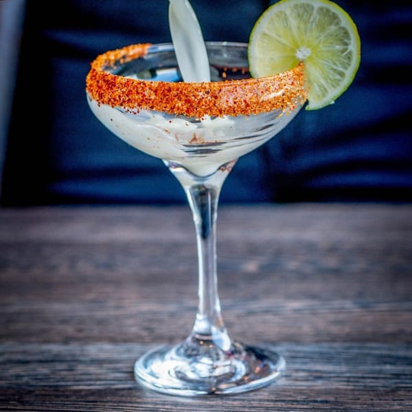 Craft Kitchen + Bar's margarita in a coupe glass with a chili-lime rim and lime wedge.